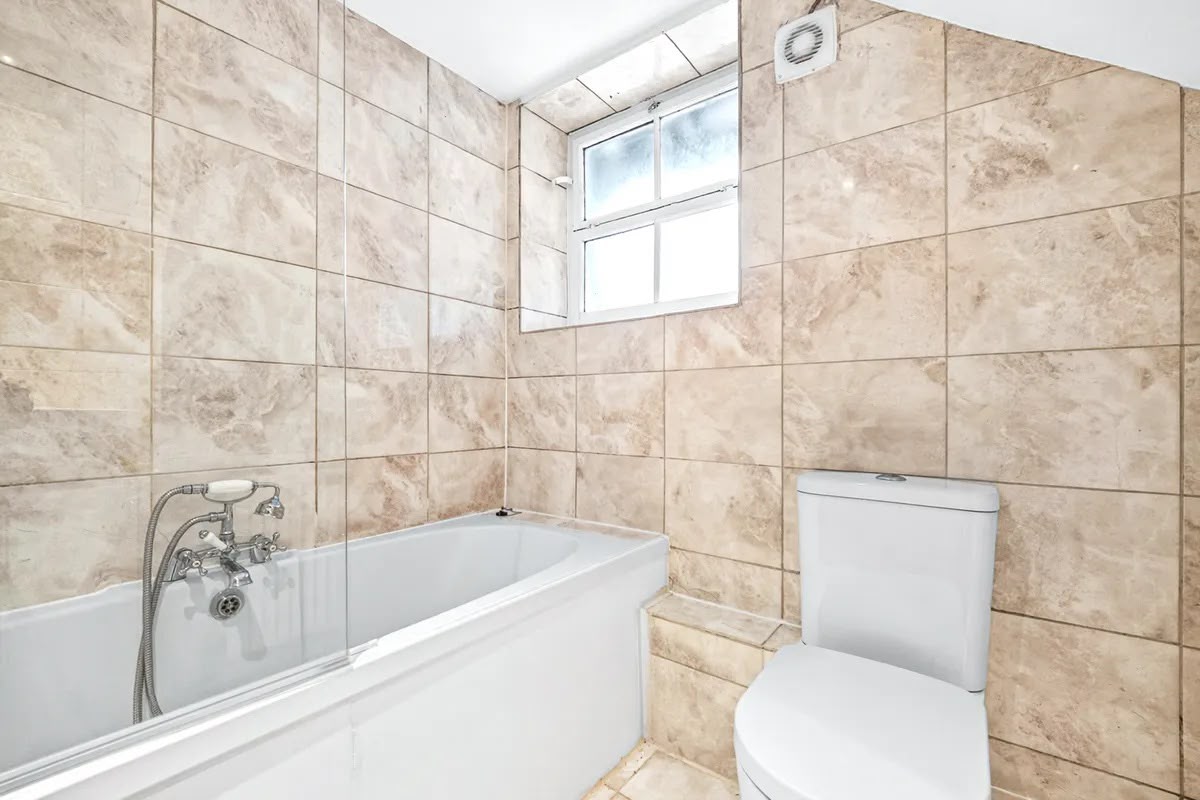 Tiled bathroom with bath and window
