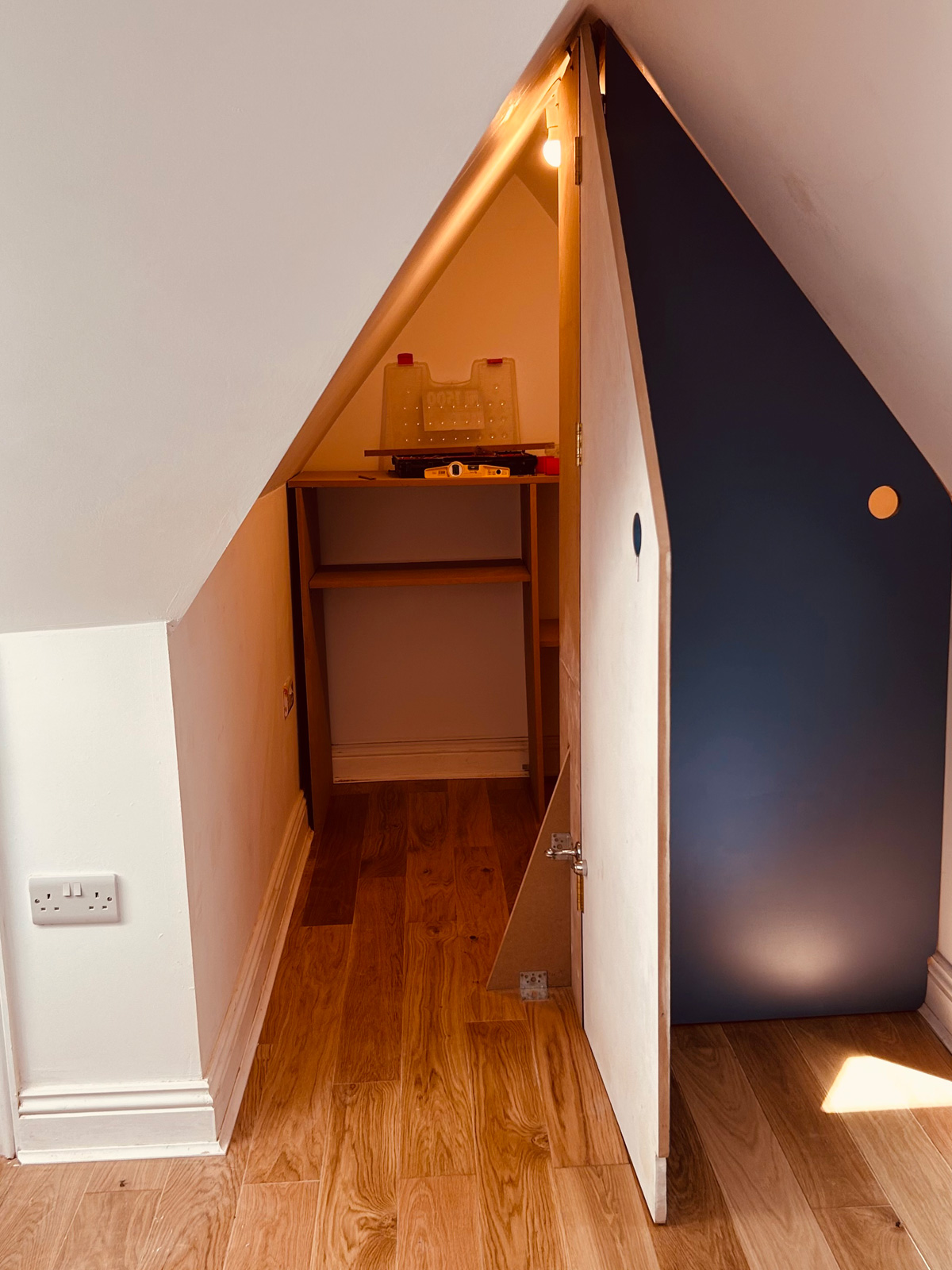 Navy eaves cupboard door opening onto a loft store