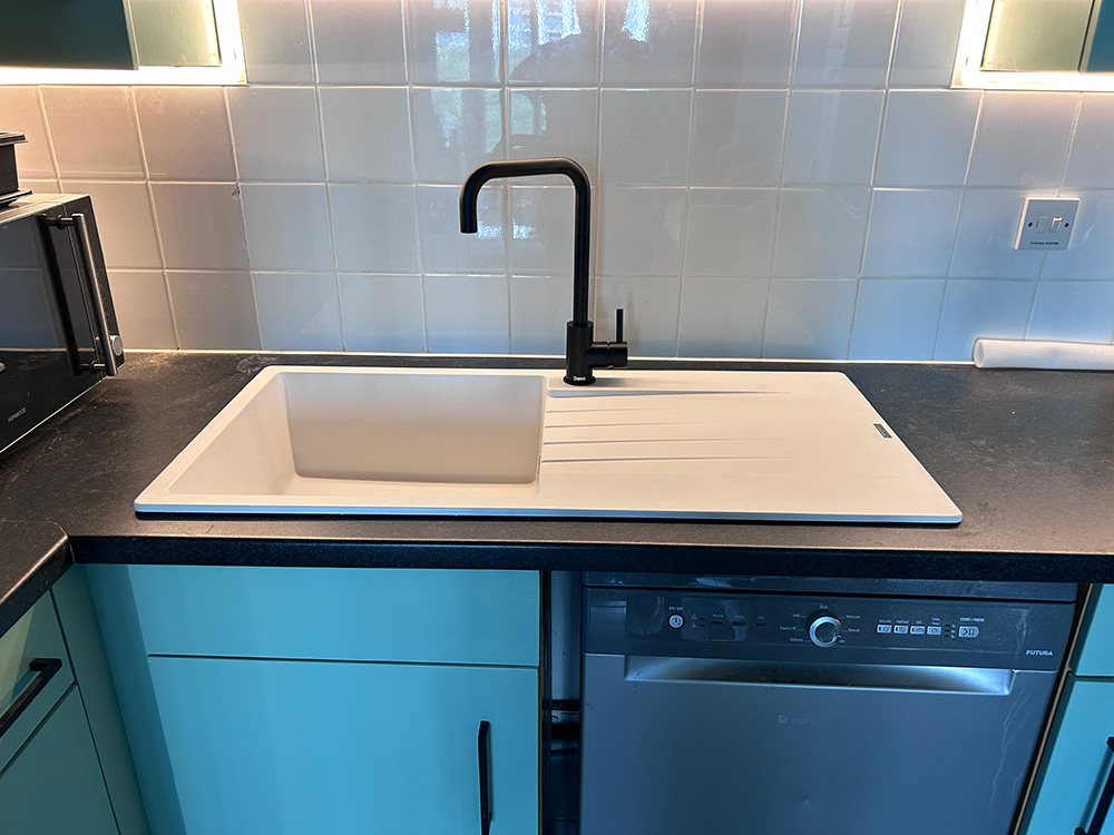 Kitchen sink with black tap and teal cabinets